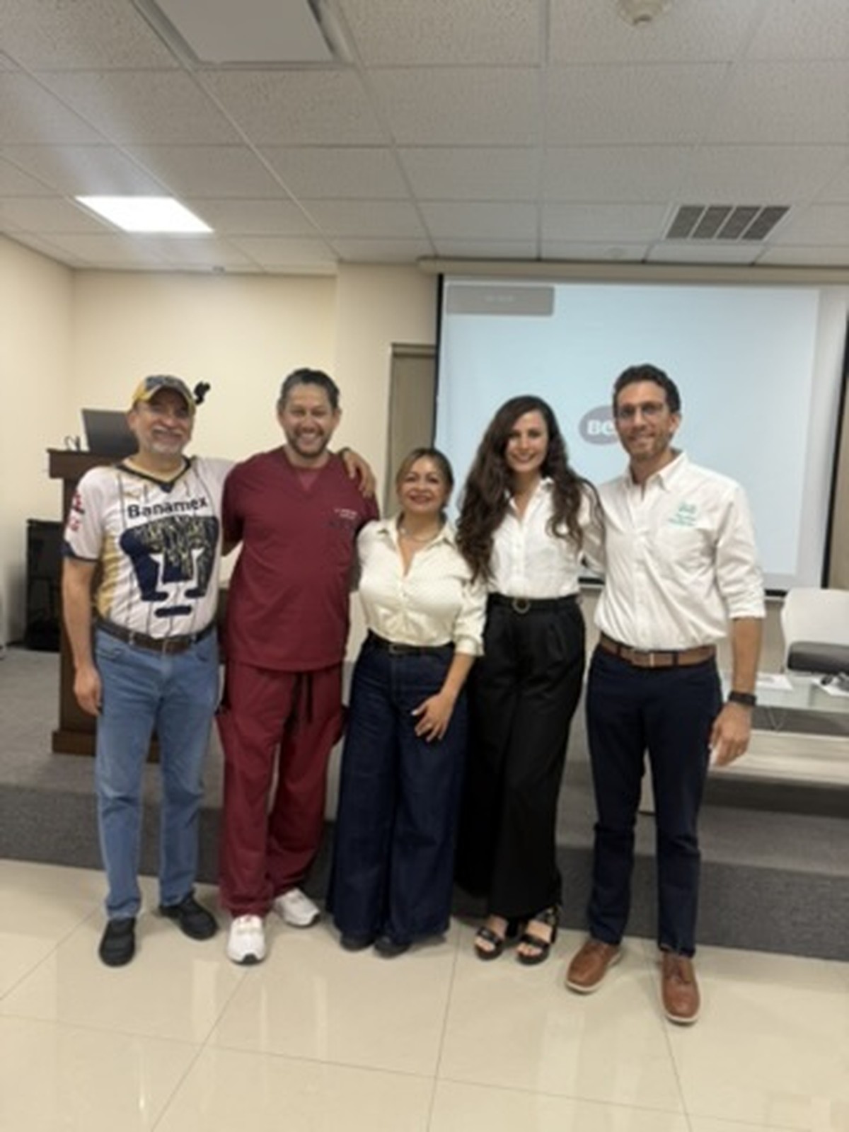 Cinco adultos en sala (jersey Pumas y scrubs)